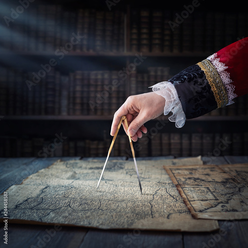 The captain of the old ship paves the course with the help of vintage maps an...