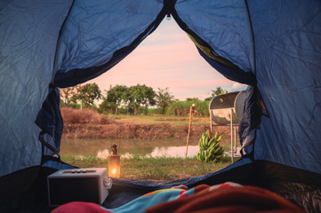 Wall Mural - View from inside of tent with relaxing and campfire near swamp