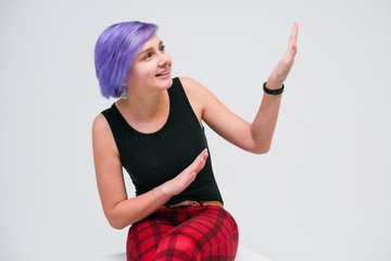 Talk to me - Concept portrait of a beautiful girl with purple hair on a white background sitting on a cube and talking.