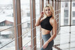 Gorgeous blonde girl in sportswear posing in the gym near window