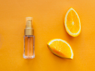 Skincare product Top view A bottle of cosmetic oil and two slices of orange are lying on a dark yellow background