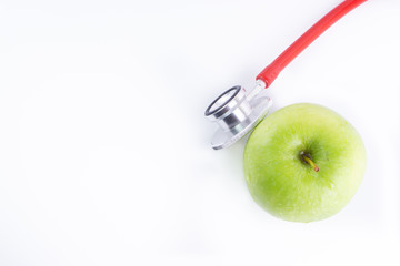 Green Apple with medical stethoscope isolated on white background for healthy eating. Selective focus and crop fragment. Healthy and copy space concept