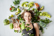 Leinwandbild Motiv Beauty portrait of a sports woman surrounded by various healthy food lying on the floor. Healthy eating and sports lifestyle concept