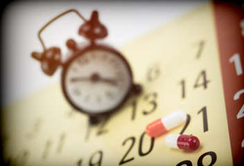 Wall Mural - Pills on a calendar next to a clock, conceptual image