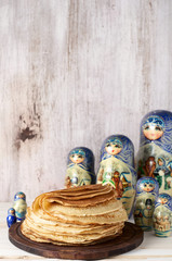 Stack of russian pancakes blini and traditional wooden dolls matrioshka