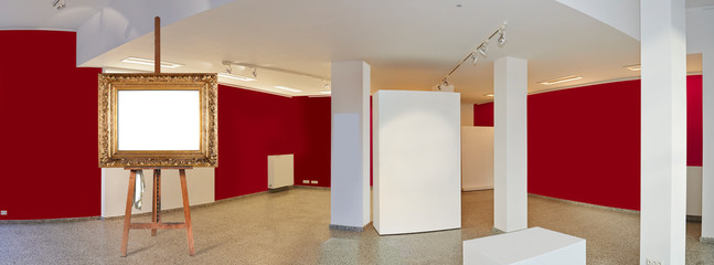 Painter's easel and empty antique golden frame in a exhibition gallery