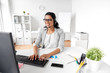 communication, business, people and technology concept - indian businesswoman or helpline operator with headset and computer talking and typing at office