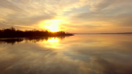 Wall Mural - Dramatic scene of beautiful sunrise over a calm lake. Perfect reflection of colorful sunrise in a frozen lake during cold morning.