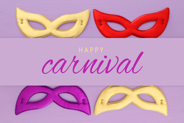 carnival party celebration concept with colorful masks over purple wooden background. Top view. Flat lay.