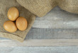 Brown chicken eggs on burlap over wooden background