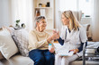 © Halfpoint - A health visitor giving a senior woman a glass of water to take pills.