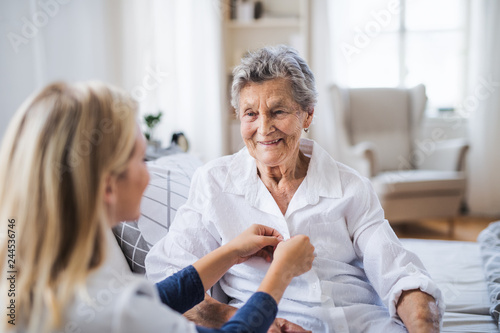 Fotografía A health visitor helping a sick senior woman sitting on bed at home