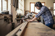 © mavoimages - Carpenter cutting wood with a mitre saw in his workshop