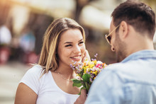 Picture Of Young Man Surprising Woman With Flowers