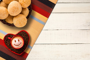 Wall Mural - Cheese buns and Red cup and coffee saucer in heart shape with decorated coffee on old wood background. Top View. Smile shape in coffee.