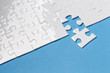 © Yeti Studio - Last piece of white puzzle ready to complete the mission on blue background
