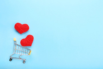 Wall Mural - Shopping cart with red rope hearts on blue background