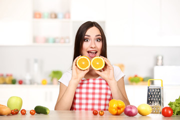 Wall Mural - Beautiful woman holding sliced orange fruit and cooking food in the kitchen