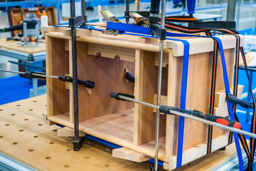 Poster - Carpenter work. Joiner's product. Tool. Furniture assembly. Pasting of wooden structures. Joiner's clamp. The product is clamped with clamps. Shop for the manufacture of furniture.