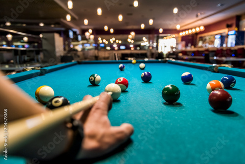 Fotomural Hand with cue aiming on billiard ball at table