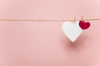 © ink drop - White and red love hearts pegged to a line against a pastel pink background