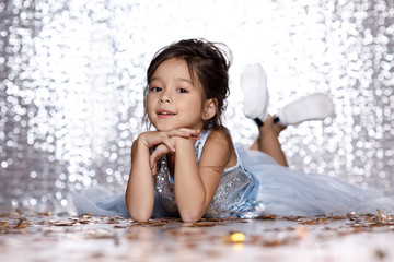 little girl in blue dress sitting on the floor with confetti