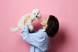Beautiful woman hugging her lovely white poodle dog puppy on pink