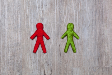 red and green yarn human figure, wooden background