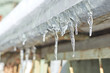 Small melting icicles hanging on the building on a winter day