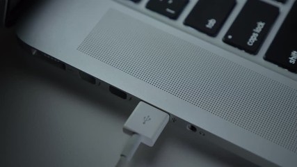 Close-up shot of hand fastly inserting usb cable into laptop on black table background.