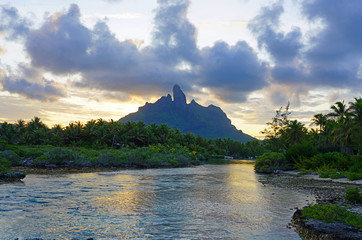 Wall Mural - Sunset view of the Mont Otemanu mountain reflecting in water over the reef between the ocean and the lagoon in Bora Bora, French Polynesia, South Pacific
