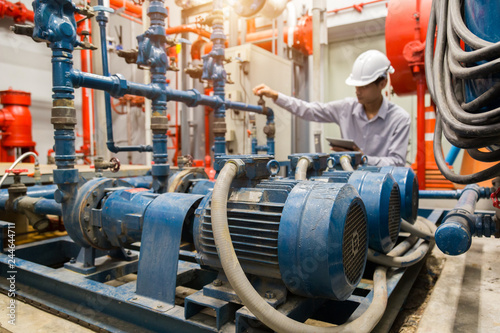 Fotomural Asian engineer maintenance checking technical data of system equipment Condenser Water pump and pressure gauge , water pump