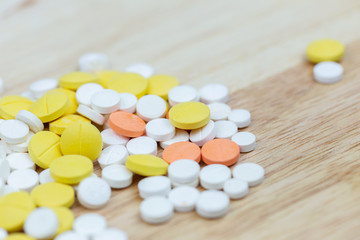 Colorful medicine pills tablets or drugs closeup on wood table background.