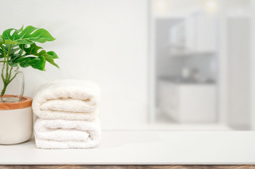 Mockup white towels and houseplant on white table with copy space for product display.