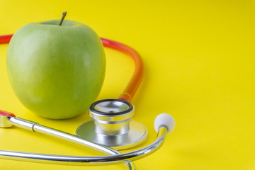 Wall Mural - Green Apple with medical stethoscope isolated on yellow background for healthy eating. Selective focus and crop fragment. Healthy, Diet and copy space concept