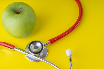 Wall Mural - Green Apple with medical stethoscope isolated on yellow background for healthy eating. Selective focus and crop fragment. Healthy, Diet and copy space concept