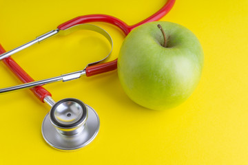 Wall Mural - Green Apple with medical stethoscope isolated on yellow background for healthy eating. Selective focus and crop fragment. Healthy, Diet and copy space concept