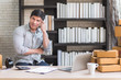© totojang1977 - Happy young Asian man at office of his business online shopping.