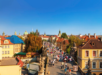 Canvas Print - Top view of center of Prague with its red roofs and tourists on the Charles bridge, Prague, Czech Republic