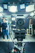 © Patrick Daxenbichler - Film camera in broadcasting studio, spotlights and equpiment, director in the background