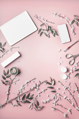 Wall Mural - Smartphone and tablet pc mock up on pastel pink desktop background with cosmetic, stationery supples and blossom branches, top view. Beauty blog and female business concept. Flat lay frame