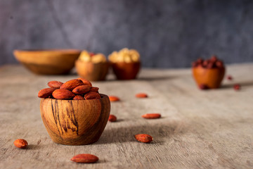 Wall Mural - Hazelnuts, cashews, Brazil nuts and almond wooden bowls on a gray background.