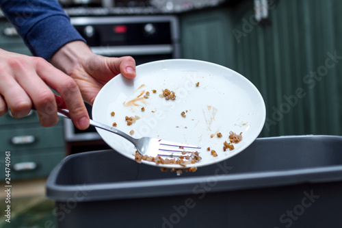 Fotografía Close up of a person throwing from a plate the leftover of buckwheat to the trash bin