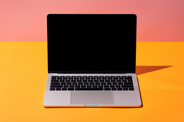 laptop with blank screen on yellow surface and pink background