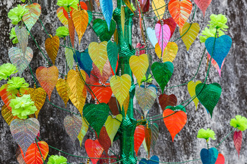 artificial colorful leaves of the bodhi tree on a gray wall background, texture and background