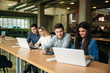 © Aleksandr - Group of college students studying in the school library, a girl and a boy are using a laptop and connecting to internet. Prepare for an exam
