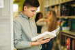 © Aleksandr - Boy student in library want to find some book. He read the book. Heplful information. study