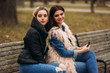 © Aleksandr - Two girls sitting on the bench outdoors. Autumn weather