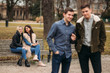 © Aleksandr - Young people having a good time in park. Male and female sitting on the bench and using phones
