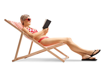 Canvas Print - Young woman in a deck chair reading a book